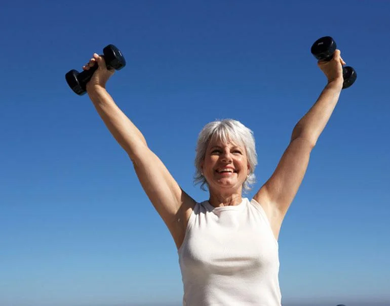 Woman happily raising dumbbells over her head