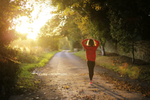 woman walking on a path at sunset - summer health