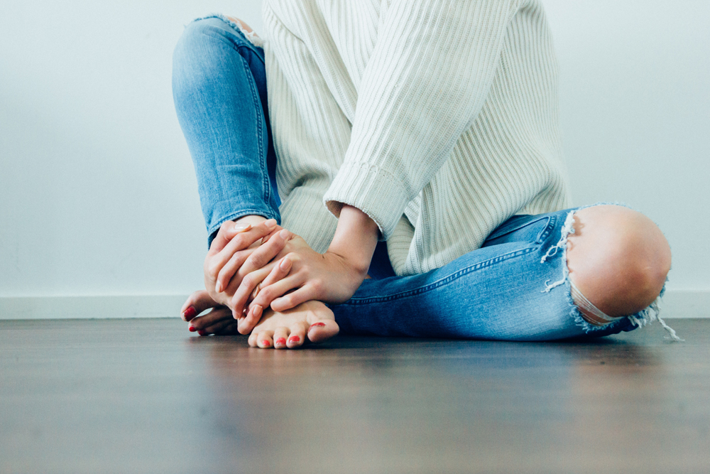 woman in ripped jeans and sweater sitting - Oak Brook well woman exam