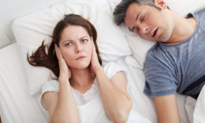 woman plugging her ears while man snores - sleep conditions Oak Brook, IL