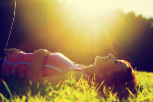 Young pretty woman lying on the grass at summer sunset.