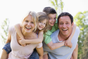 Couple giving two young children piggyback rides smiling